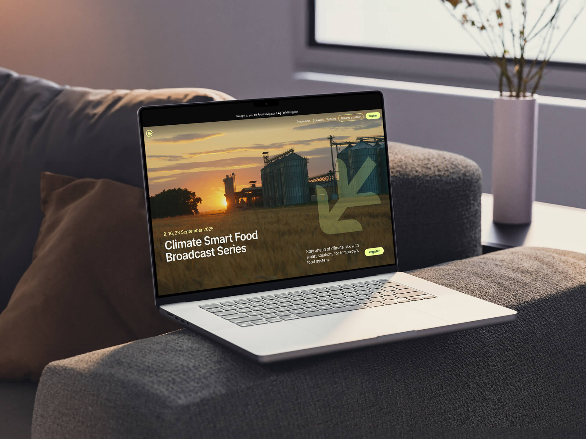 A laptop open on a sofa arm showing the homepage hero of the Climate Smart Food website